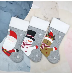 Three grey felt Christmas stockings with Santa, Snowman, and Reindeer on marble background