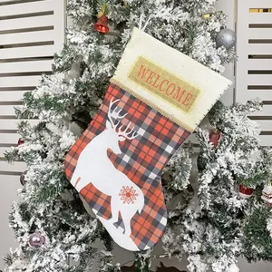 Plaid Christmas stocking with reindeer print and Welcome text hanging on a tree
