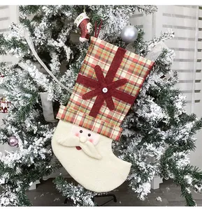 Detail of Santa Claus stocking hanging on a snowy Christmas tree with red plaid fabric