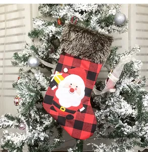 Detail eines rot-schwarz karierten Weihnachtssocken mit Kunstpelzrand und Weihnachtsmann