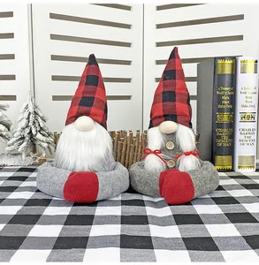 Close-up of Christmas gnome pair with red plaid hats and grey plush bodies on tabletop