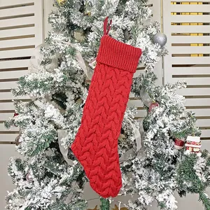 Classic red cable knit Christmas stocking with hanging loop on snow-dusted tree