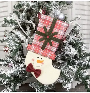 Detail of a snowman Christmas stocking hanging on a snowy tree with plaid pattern
