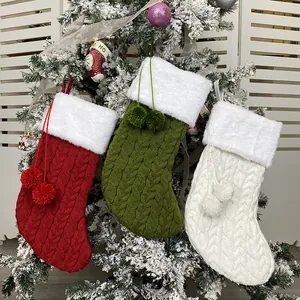 Three knitted Christmas stockings in red, green, and white hanging on a festive tree