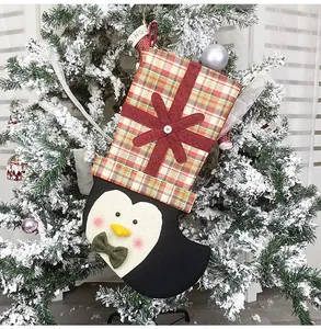 Detailed close-up of a Christmas penguin stocking hanging on a snowy holiday tree branch