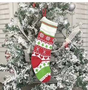 Dettaglio di una calza di Natale in maglia con fiocchi di neve appesa a un albero innevato