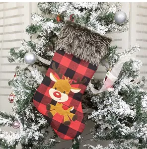 Detail eines Weihnachtsstrumpfs mit Büffelkaromuster und Rentier-Stickerei am Tannenbaum