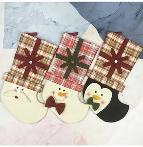 Detailed view of plaid Christmas stockings featuring Santa, snowman and penguin characters