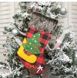 Detail eines Weihnachtsstrumpfs mit Karomuster und Kunstpelz an einem Baum