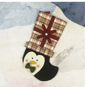 Detail of penguin Christmas stocking featuring red plaid pattern and felt snowflake