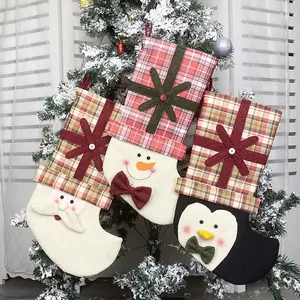 Three Christmas stockings with Santa, Snowman, and Penguin hanging on a snowy tree