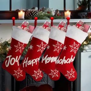 Close-up of red knit Christmas stockings with white snowflake embroidery and festive text