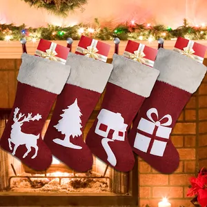 Close-up of four red burlap Christmas stockings with white festive patterns on a fireplace