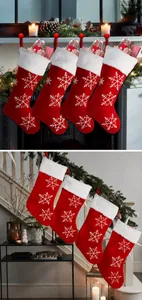 Set of 4 red plush Christmas stockings with white snowflakes and festive text on a fireplace
