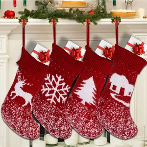 Set of 4 red knitted Christmas stockings with reindeer and snowflake patterns hanging on mantle