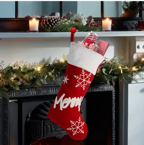 Macro detail of red knitted Christmas stocking with white Merry embroidery and snowflakes