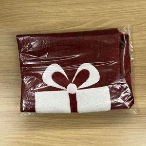 Macro view of burgundy burlap Christmas gift bag with white felt bow on wood surface