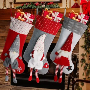 Drie kerstkousen met 3D-kabouters aan de open haard met een besjeskrans decoratie