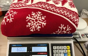 Detailopname van een rode gebreide kerstboomschort met sneeuwvlokpatroon op een weegschaal