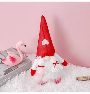 Detalle de un gnomo de San Valentín con gorro rojo y corazón sobre alfombra blanca suave