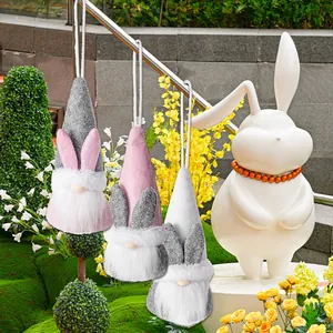 Three Easter gnome plush ornaments with rabbit ears hanging in a garden setting