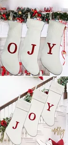 Détail de trois chaussettes de Noël en tricot ivoire avec lettres JOY rouges