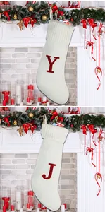 Détail de chaussette de Noël en tricot crème avec lettre Y rouge brodée sur décor de cheminée