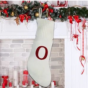 Gros plan d'une chaussette de Noël en tricot blanc avec la lettre rouge O décorée