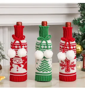 Detailed view of three knitted Christmas wine bottle covers with snowman and tree patterns