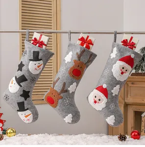 Detailed close-up of grey felt Christmas stockings with snowman and reindeer embroidery