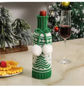Detail of green and white knitted Christmas wine bottle cover with tree pattern and bow