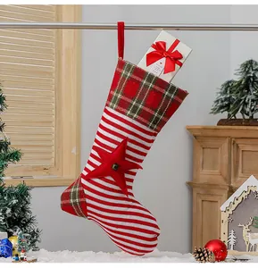 Close-up of a striped knitted Christmas stocking with a bell-accented star on a cozy shelf
