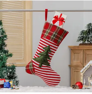 Close-up of red striped knitted Christmas stocking with green tree and gift box inside
