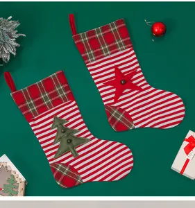 Close-up of knit Christmas stockings with plaid patterns and tree ornaments on green background