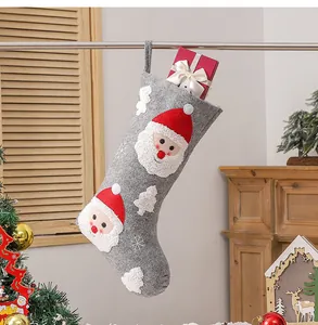 Detailed view of grey Christmas stocking with Santa embroidery and festive red gift box