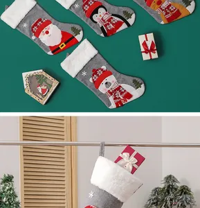 Detail of grey knit Christmas stockings with plush cuffs, Santa, penguin and elk embroidery