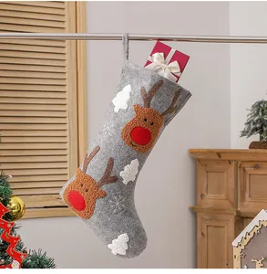 Detail of Christmas stocking with reindeer embroidery and a red gift box hanging decoration