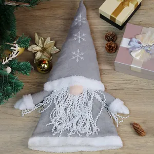 Grey knitted Christmas gnome plush tree topper with snowflake embroidery on wooden table