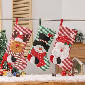 Three Christmas stockings with 3D Santa, snowman, and reindeer designs hanging by tree