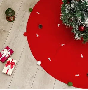 Detail of red Christmas tree skirt with plush pom-poms and white tree embroidery