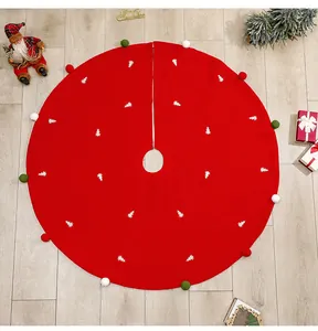 Detail of red Christmas tree skirt with white tree embroidery and colorful pom-poms