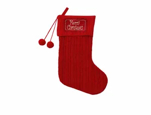 Detail of red cable knit Christmas stocking with pom-poms and Merry Christmas label