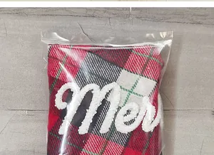 Detalle de funda de botella de vino a cuadros rojos y negros con letras Merry de felpa