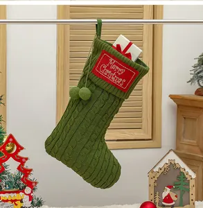 Detail van groene gebreide kerstsok met geborduurde patch en witte geschenkverpakking