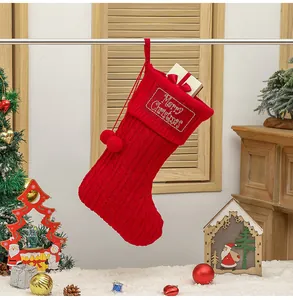 Detail van rode gebreide kerstsok met borduursel en zachte decoratieve pompon hangers