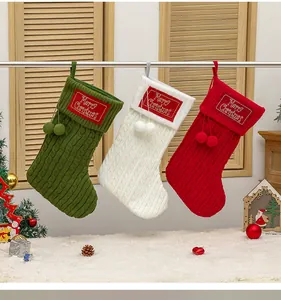 Detail van kabelgebreide kerstsokken in rood, groen en ivoor met zachte pompons