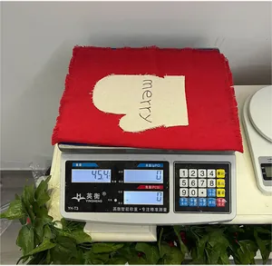 Close-up of a red linen Christmas napkin with merry embroidery on an electronic scale