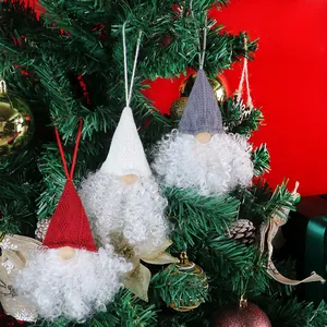 Tre ciondoli a forma di gnomo di Natale in rosso, bianco e grigio su un albero