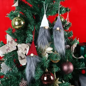 Tre gnomi natalizi appesi con cappelli a maglia e barbe di pelliccia finta su albero