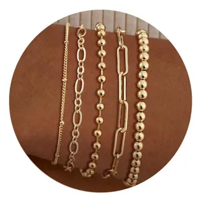 Detalle de cinco pulseras bañadas en oro en capas sobre la muñeca de una mujer